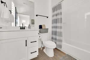 Full bathroom with hardwood / wood-style flooring, toilet, vanity, and shower / tub combo with curtain