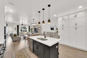 Kitchen featuring hanging light fixtures, sink, white cabinets, a kitchen island with sink, and stainless steel appliances