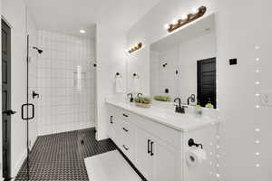 Bathroom featuring tile patterned floors, a shower with door, and vanity