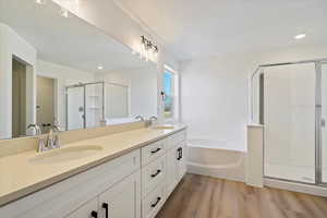 Bathroom featuring independent shower and bath, vanity, hardwood / wood-style floors, and a textured ceiling