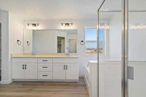 Bathroom with a washtub, hardwood / wood-style floors, vanity, and a textured ceiling