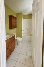 Ensuite Full bathroom in primary bedroom featuring toilet, tile patterned flooring, vanity, and shower / bathing tub combination