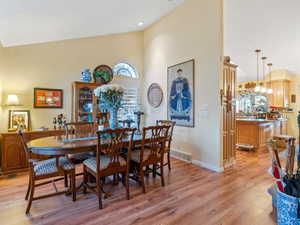 Dining area with light wood-type flooring, an inviting chandelier, and lofted ceiling