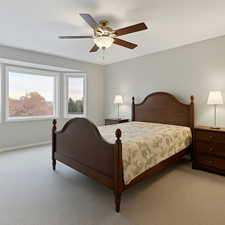 Primary bedroom featuring light carpet, baseboards, and ceiling fan