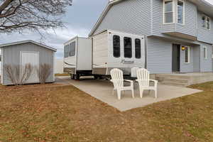 Rear view of property with a patio area, a shed, and an outbuilding and RV pad.
