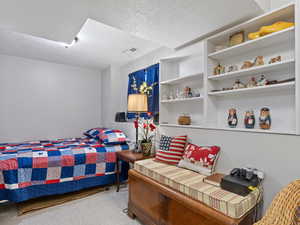 Fourth bedroom with a textured ceiling and light colored carpet