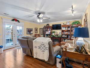Living room with wood-type flooring, french doors, rail lighting, ornamental molding, and ceiling fan