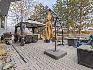 Deck featuring a gazebo, a fire pit, and a grill