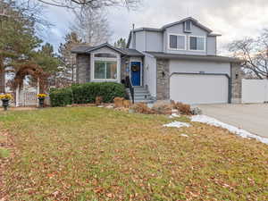 View of front property featuring a garage and a front lawn