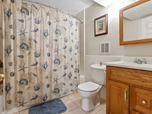 Third full bathroom with toilet, vanity, tile patterned flooring, tile walls, and shower / bath combo with shower curtain
