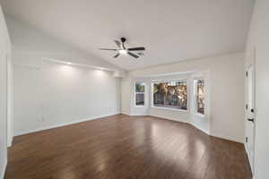 Spare room with ceiling fan, vaulted ceiling, and dark hardwood / wood-style floors