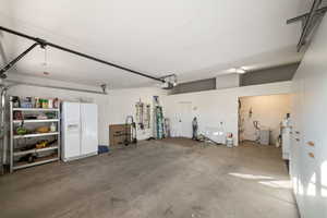 Garage featuring a garage door opener and white refrigerator with ice dispenser