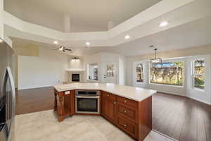 Kitchen with ceiling fan with notable chandelier, pendant lighting, lofted ceiling, a kitchen island, and stainless steel appliances