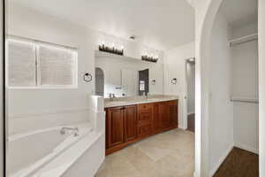 Bathroom featuring vanity, ornamental molding, and a bath