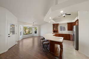 Kitchen with a kitchen island, a kitchen bar, sink, hanging light fixtures, and stainless steel refrigerator