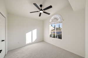 Unfurnished room with ceiling fan, light colored carpet, and vaulted ceiling