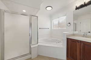 Bathroom featuring vanity, tile patterned floors, crown molding, and plus walk in shower