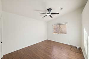 Unfurnished room featuring hardwood / wood-style flooring, lofted ceiling, and ceiling fan