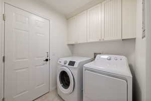 Clothes washing area featuring washing machine and dryer and cabinets