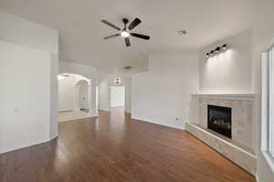 Unfurnished living room featuring hardwood / wood-style floors, a fireplace, ceiling fan, vaulted ceiling, and decorative columns