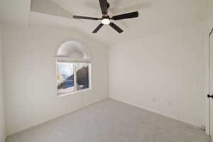 Carpeted empty room with vaulted ceiling and ceiling fan