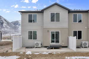 Snow covered rear of property featuring a mountain view, a patio, and ac unit