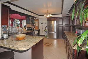 Kitchen featuring sink, decorative light fixtures, light stone countertops, and appliances with stainless steel finishes