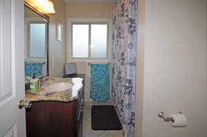 Bathroom with a shower with curtain, tile patterned flooring, and vanity