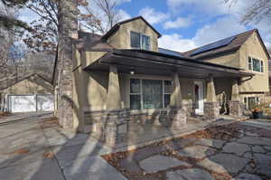 View of front of house with a porch, a garage, solar panels, and an outdoor structure