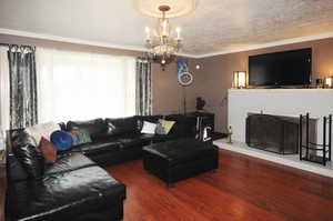 Living room with hardwood / wood-style floors, crown molding, a notable chandelier, and a textured ceiling