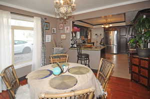 Tiled dining room featuring ornamental molding and an inviting chandelier