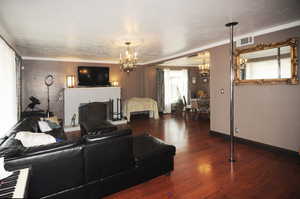 Living room featuring a chandelier, crown molding, and dark wood-type flooring