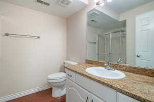 Bathroom with a shower with shower door, vanity, wood-type flooring, and toilet