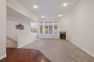 Unfurnished living room featuring carpet and crown molding