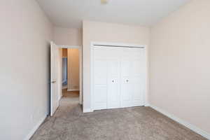 Unfurnished bedroom with light colored carpet and a closet