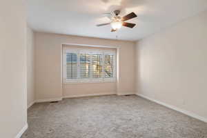 Carpeted spare room featuring ceiling fan