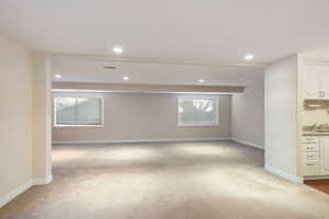 Carpeted spare room featuring a healthy amount of sunlight and sink