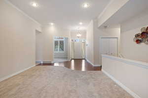 Carpeted foyer with crown molding and an inviting chandelier