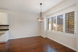 Unfurnished dining area featuring dark wood-type flooring