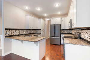 Kitchen with sink, white cabinets, stainless steel appliances, and dark stone counters