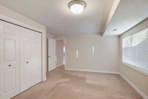 Unfurnished bedroom with light carpet and a closet