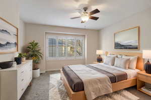 Carpeted bedroom with ceiling fan. Virtually staged.