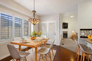 Dining area with dark wood-type flooring and crown molding. Virtually staged.