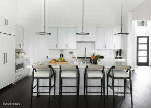 Kitchen with decorative light fixtures, a center island with sink, and white cabinetry