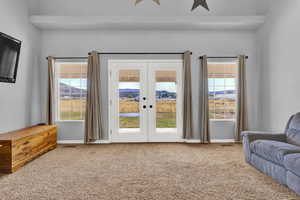 Carpeted living room with a mountain view, a wealth of natural light, and french doors