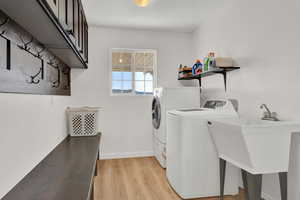 Washroom featuring cabinets, light hardwood / wood-style flooring, and washing machine and dryer