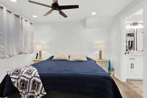 Carpeted bedroom with ensuite bath and ceiling fan