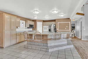 Kitchen with light brown cabinets, a center island, stainless steel appliances, and light tile patterned flooring