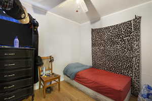 Bedroom featuring hardwood / wood-style floors, ceiling fan, and ornamental molding