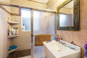 Bathroom featuring a shower with shower door and vanity